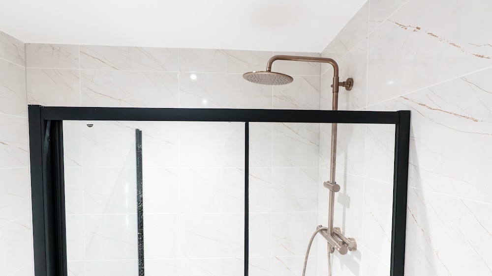 Walk-in shower with marble-effect tiling and a black frame